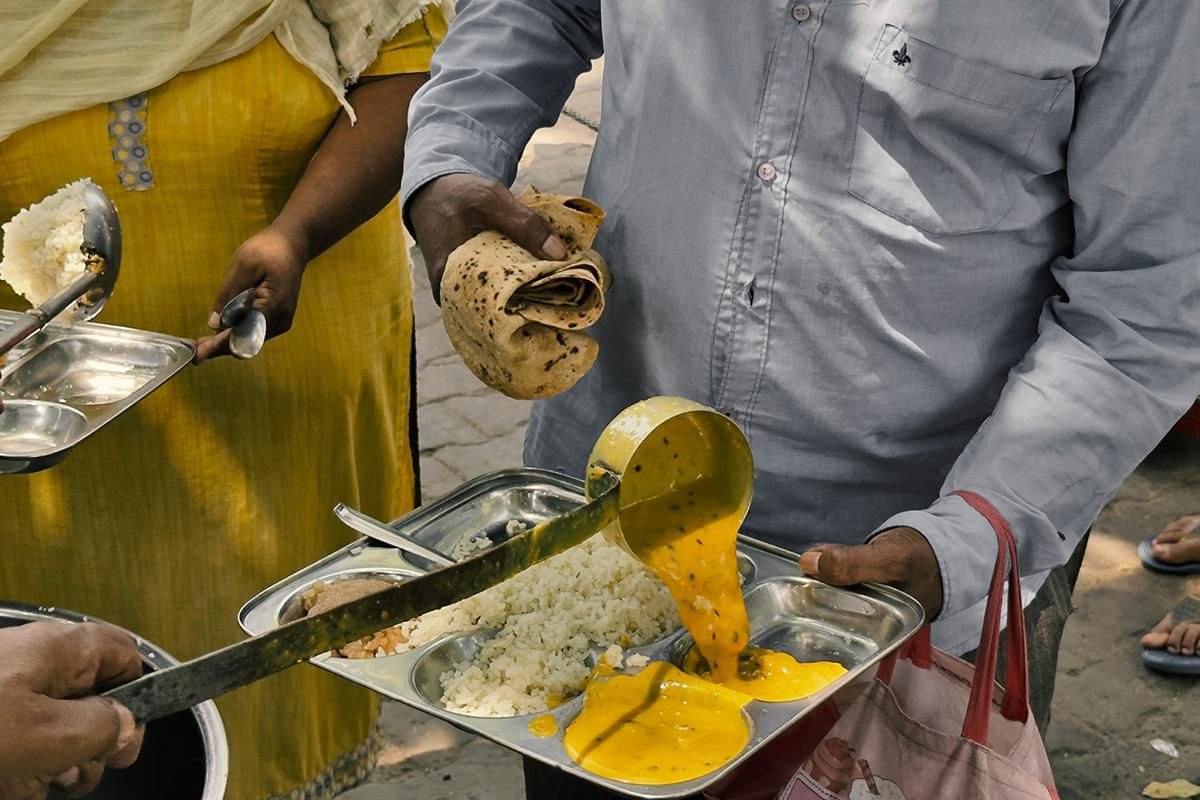 Serving dal-rice meals in steel thali to community